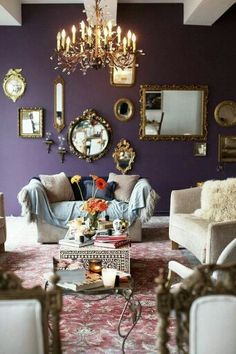 a living room filled with furniture and mirrors on the wall next to a chandelier