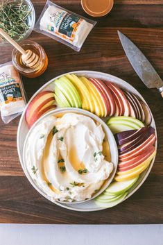 an assortment of fruits and dips on a plate with a wooden cutting board next to it