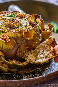 someone is holding up some artichokes on a plate with other food items