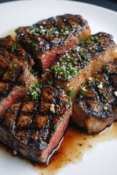 three steaks on a white plate with garnish and seasoning sprinkles