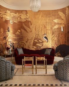 a living room filled with furniture and a wall covered in gold leafy art work