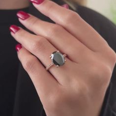 a woman's hand wearing a ring with an oval shaped gray stone on it