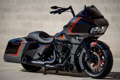 a motorcycle parked in front of a brick wall next to a cement wall with an orange and black stripe on it