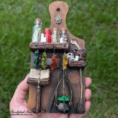 a hand holding a miniature wooden shelf with various items on it