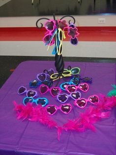 a purple table topped with lots of heart shaped sunglasses and a vase filled with flowers