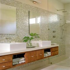 a bathroom with two sinks and a large mirror in it's center, next to a walk in shower