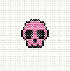 a cross stitch skull with pink and black dots on it's face, in the middle