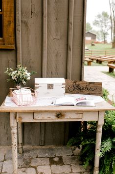 an old table with some books and flowers on it next to a wooden fenced in area