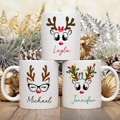 three coffee mugs decorated with reindeer's and glasses on top of a wooden table