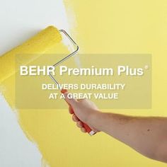 a person holding a paint roller and painting the wall with bright yellow paint on it