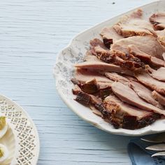 sliced ham on a white plate next to silverware