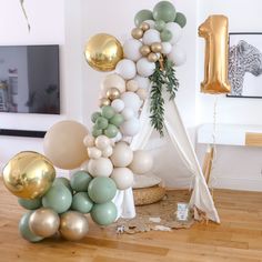 the balloon arch is decorated with gold, white and mint green balloons for an elegant birthday party