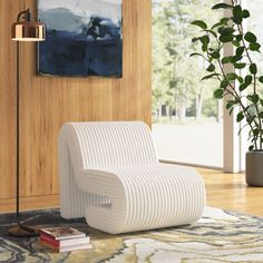 a white chair sitting on top of a wooden floor next to a lamp and potted plant