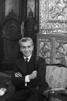 an old black and white photo of a man in a suit sitting on a chair