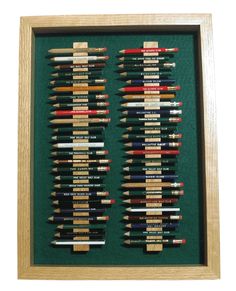 a group of pencils sitting on top of a green surface in a wooden frame