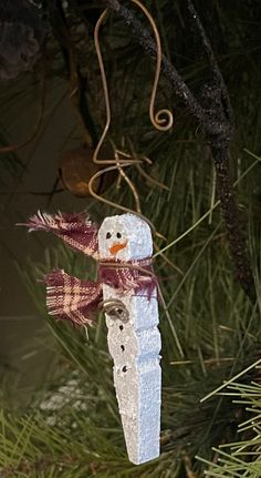 a snowman ornament hanging from a pine tree