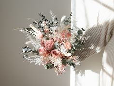 a woman holding a bouquet of flowers in her hand with sunlight coming through the window