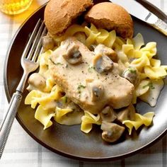 a plate topped with pasta and meat covered in mushroom gravy next to a fork