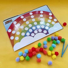 some pom poms are laying on the table next to a rainbow craft kit