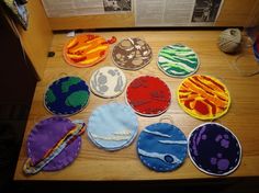 several different colored circles are sitting on a wooden table with yarn and thread in front of them