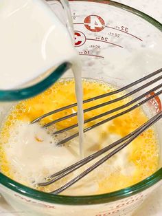 eggs being whisked in a mixing bowl with milk and other ingredients to make an omelet