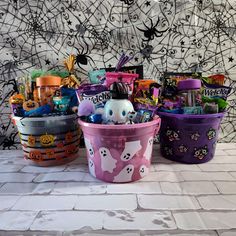 three plastic buckets filled with candy and candies on top of a white tiled floor