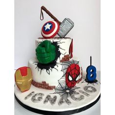 a three tiered cake decorated with avengers symbols