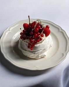 a white plate topped with a cake covered in whipped cream and cherries on top of it