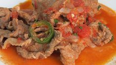 some meat and vegetables are on a white plate with red sauce in the middle,