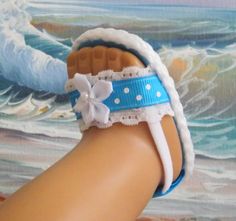 a doll's foot wearing a blue and white bracelet