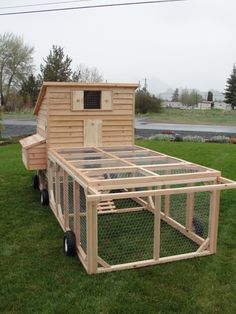 a chicken coop sitting on top of a trailer in the grass