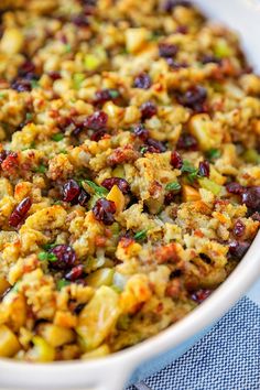 a casserole dish filled with stuffing and cranberries on a blue cloth