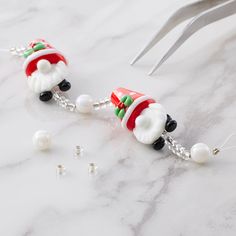 santa clause beaded earrings with pearls and chains on marble countertop next to scissors