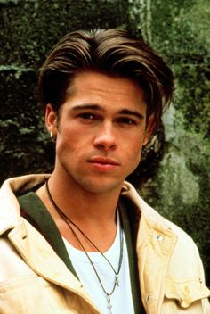 a close up of a person wearing a jacket and necklace with a bird on his shoulder