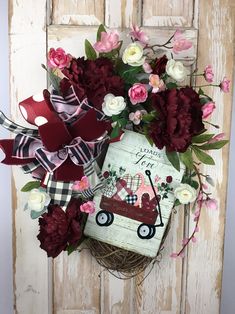 a bouquet of flowers on top of a wooden door with an old fashioned wagon and bow