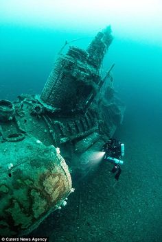 an underwater view of a ship wreck in the ocean with scuba gear on it's side