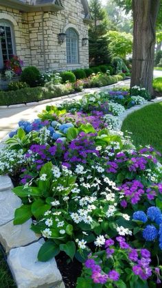 a flower bed with purple and white flowers in front of a house