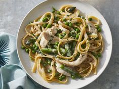 a white plate topped with pasta and peas next to a blue napkin on top of a table