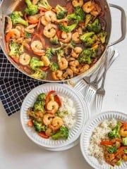 shrimp and broccoli stir fry in a skillet with rice on the side