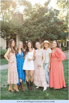 a group of women standing next to each other on top of a grass covered field