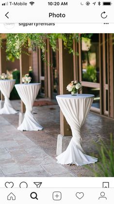 two tables with white tablecloths and flowers on them in front of a building