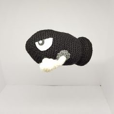 a black and white stuffed animal hanging from the ceiling in front of a white background