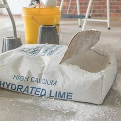 a white bag sitting on the ground next to a yellow trash can