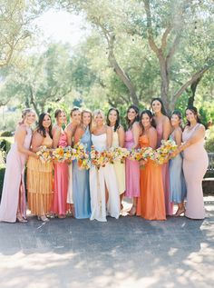 a group of women standing next to each other holding bouquets in their hands and smiling at the camera