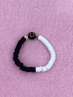 a black and white bracelet with a smiley face charm