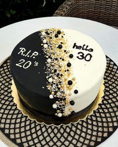 a white and black cake with gold sprinkles sitting on top of a table