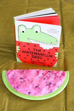 the watermelon seed book is next to a slice of watermelon on a plate