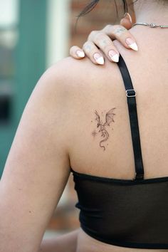 the back of a woman's shoulder with a dragon tattoo on her left arm