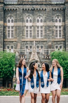 three women in blue and white dresses are standing together outside an old building with large windows