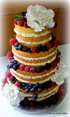 a multi layer cake with berries and flowers on top